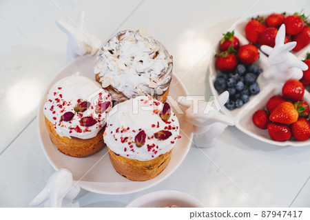 decorated panettones and cruffins on serving plates with rabbits. easter cakes. decorated panettones and cruffins on serving plates with rabbits. easter cakes. 87947417