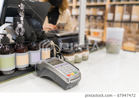 Closeup of credit card terminal in zero waste local shop. POS terminal in local grocery store Closeup of credit card terminal in zero waste local shop. POS terminal in local grocery store 87947472