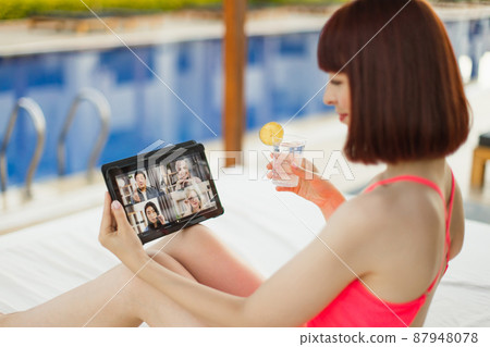 Woman in pink swimwear, near blue pool, drinking lemonade and speaking with four friends Woman in pink swimwear, near blue pool, drinking lemonade and speaking with four friends 87948078
