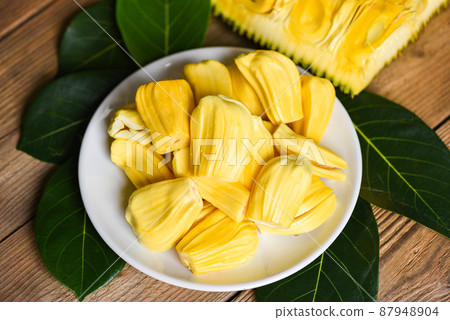 Ripe jackfruit peeled tropical fruit fresh from jackfruit tree, jackfruit on white plate with leaf on wooden background 87948904