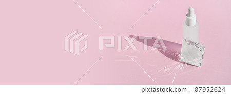 Serum cosmetic bottle mockup with acrylic transparent solid block pedestal on pink background, with crystal glass prism refracting light effects and rays of light. Serum cosmetic bottle mockup with acrylic transparent solid block pedestal on pink background, with crystal glass prism refracting light effects and rays of light. 87952624