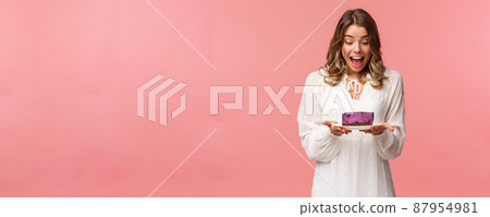 Holidays, spring and party concept. Portrait of happy and excited young blond girl decided start day with sweets, look amazed and cheerful and piece of delicious cake, cant wait to eat it 87954981