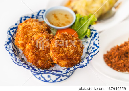 Deep-fried shrimp Cake on a beautiful plate with plum sauce, close-up image of deep-fried shrimp cake with blurred other food on white background, an image of crispy Thailand food. 87956559