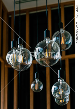 Close up group of beautiful round shape light bulb from ceiling, transparent hanging glass light bulbs for interior decoration, vertical image. 87956609