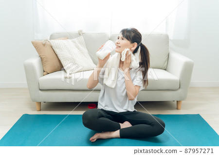 中年女性在房間裡做瑜伽(喝蛋白質) 中年女性在房間裡做瑜伽(喝蛋白質) 87957271
