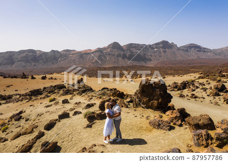 People in love kiss in the crater of the Teide volcano. Desert landscape in Tenerife. Teide National Park. Desert crater of the Teide volcano. Tenerife, Canary Islands People in love kiss in the crater of the Teide volcano. Desert landscape in Tenerife. Teide National Park. Desert crater of the Teide volcano. Tenerife, Canary Islands 87957786