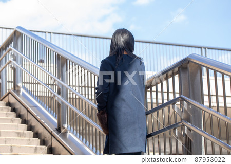 A woman climbing the stairs of a pedestrian bridge Pedestrian bridge 87958022