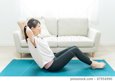 Middle-aged woman doing abdominal muscles in the room Middle-aged woman doing abdominal muscles in the room 87958990