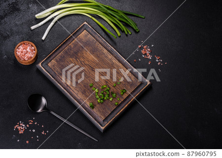 Black metal spoon and rectangular cutting board on black concrete background 87960795