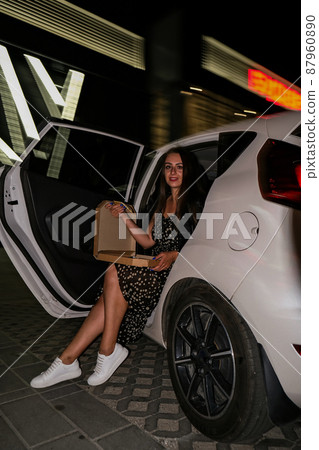 Hanging out. Young casually woman on a parking site eating pizza at night. Lifestyle millennial gen z generation Hanging out. Young casually woman on a parking site eating pizza at night. Lifestyle millennial gen z generation 87960890