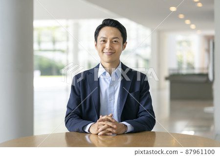 A businessman in his thirties smiling looking at the camera 87961100