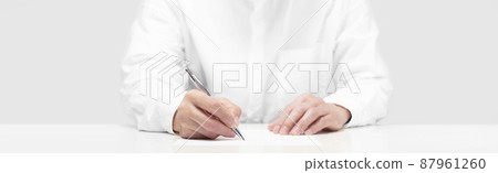 A person writing on paper with a pen 87961260