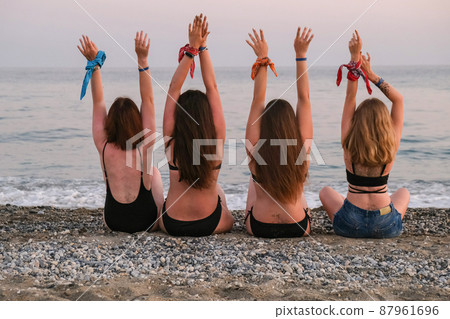 Four girls friends lying on beach stretching up slender legs sea island in the background having fun on vacation. Together. Woman on the beach relaxing concept. Beautiful vacation summer holiday Four girls friends lying on beach stretching up slender legs sea island in the background having fun on vacation. Together. Woman on the beach relaxing concept. Beautiful vacation summer holiday 87961696