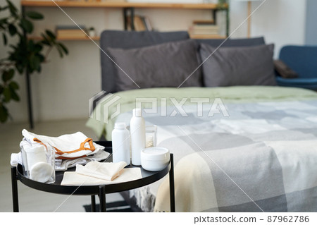 Group of bodycare items for baby on small round table against double bed Group of bodycare items for baby on small round table against double bed 87962786
