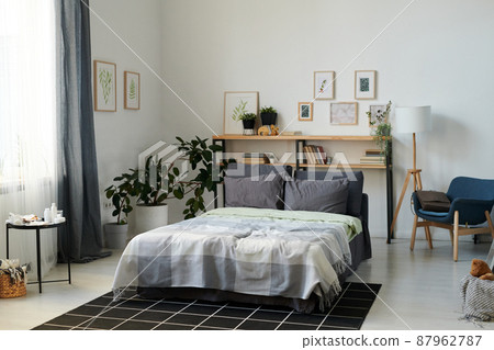 Part of spacious bedroom with double bed and shelves in the center 87962787