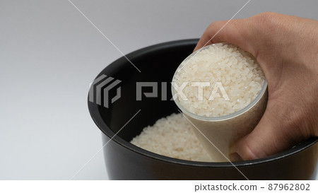 用量杯將白米放入電飯煲內鍋的場景 87962802