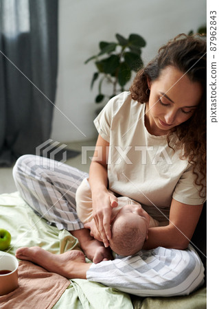 Young brunette woman looking at sleeping baby on her hands Young brunette woman looking at sleeping baby on her hands 87962843