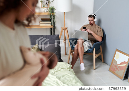 Young contemporary businessman in headphones texting in mobile phone Young contemporary businessman in headphones texting in mobile phone 87962859