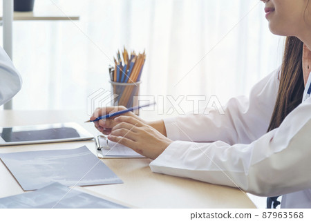 Close up hands of women doctor write prescription medical lab hospital. Crop asian women hand doctors working in medical clinic looking CAT scan xray film. Doctor with stethoscope writing on notepad Close up hands of women doctor write prescription medical lab hospital. Crop asian women hand doctors working in medical clinic looking CAT scan xray film. Doctor with stethoscope writing on notepad 87963568