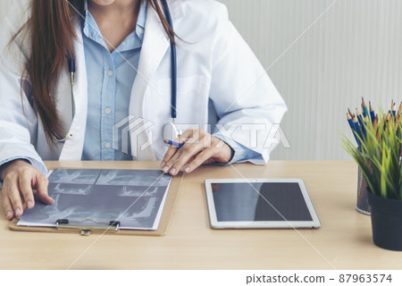 Close up hands of women doctor write prescription medical lab hospital. Crop asian women hand doctors working in medical clinic looking CAT scan xray film. Doctor with stethoscope writing on notepad Close up hands of women doctor write prescription medical lab hospital. Crop asian women hand doctors working in medical clinic looking CAT scan xray film. Doctor with stethoscope writing on notepad 87963574