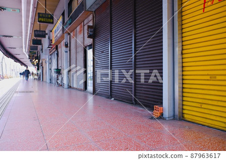 A shopping street where shutters are closed with little traffic 87963617