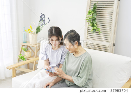 Grandson and grandmother smartphone living room Grandson and grandmother smartphone living room 87965704