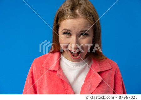Young woman laughing cheerfully in a studio on blue background 87967023