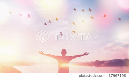 Happy backpack man raise hand up and birds flying on sunset sky at river background. Travel adventure and freedom feel good concept.  87967198