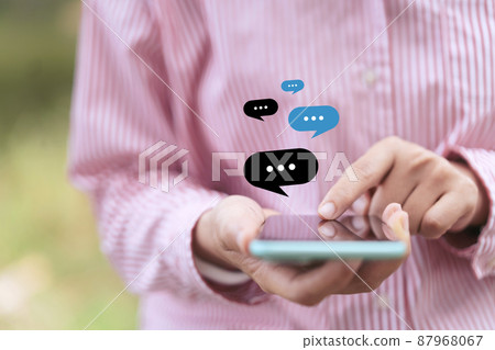 Close up woman hand hold using smart phone with chat icon flying at outdoor nature park background. Copy space of technology business and travel holiday concept.  87968067