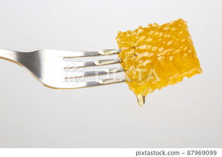 Drops of fresh honey drip from wax honey on a table fork. vitamin nutrition and bee product Drops of fresh honey drip from wax honey on a table fork. vitamin nutrition and bee product 87969099
