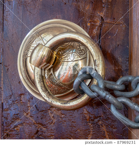 Antique copper ornate door knocker over an aged wooden door and rusted chain, Eyup Sultan Mosque, Istanbul, Turkey Antique copper ornate door knocker over an aged wooden door and rusted chain, Eyup Sultan Mosque, Istanbul, Turkey 87969231