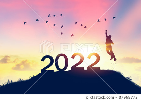 Man jumping on sunset sky with birds flying at top of mountain and number like 2022 abstract background. Happy new year and holiday concept.  87969772