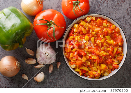 Delicious summer sofrito sauce from peppers, tomatoes, garlic and onions close-up in a plate. horizontal top view 87970300