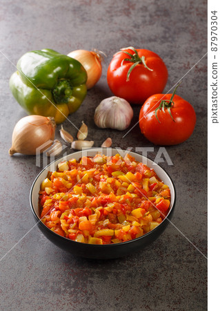 Mediterranean sofrito sauce from ripe peppers, tomatoes, garlic and onions close-up in a plate. Vertical 87970304