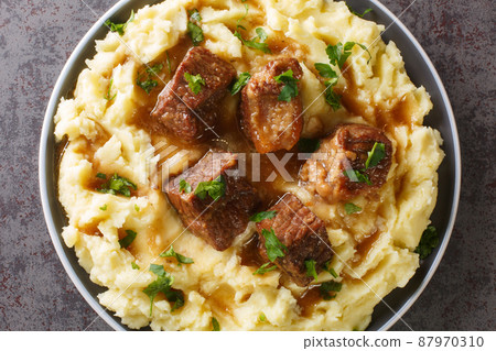 Greek Slow Sofrito braised beef with spicy gravy garnished with mashed potatoes close-up in a plate. horizontal top view 87970310