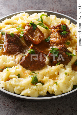 Greek sofrito is a dish consisting of tender cuts of beef slowly sauteed in a flavorful sauce served with mashed potatoes closeup in the plate. Vertical 87970318