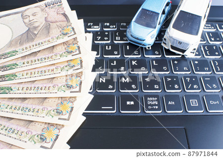 A black laptop keyboard, a 10,000 yen note, a light blue compact car, and a white minivan 87971844