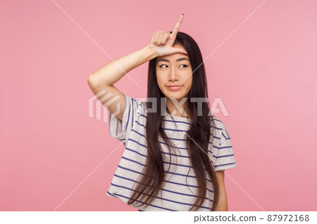 I lost, my fault. Upset girl with brunette hair in striped t-shirt showing loser gesture on forehead and looking frustrated, depressed about failure. indoor studio shot isolated on pink background I lost, my fault. Upset girl with brunette hair in striped t-shirt showing loser gesture on forehead and looking frustrated, depressed about failure. indoor studio shot isolated on pink background 87972168