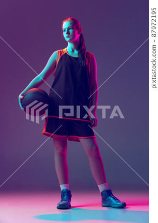 Portrait of teenager basketball player in uniform posing isolated over gradient pink purple background in neo Portrait of teenager basketball player in uniform posing isolated over gradient pink purple background in neo 87972195