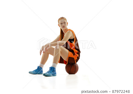 Portrait of teen girl, basketball player sitting on ball, resting isolated over white studio background 87972248