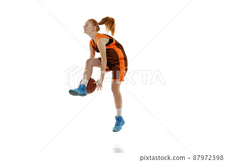 Portrait of young active girl, basketball player training, dribblig ball in a jump isolated over white studio background. 87972398