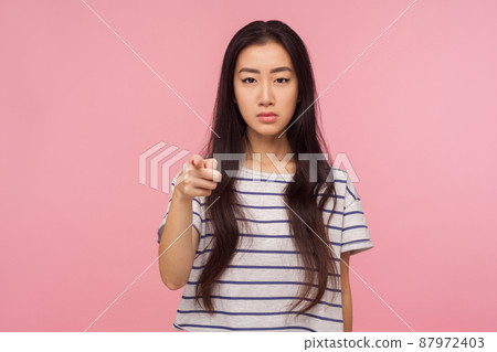 Hey you, Portrait of serious girl with long brunette hair pointing finger to camera and looking with angry strict expression, accusing in failure. indoor studio shot isolated on pink background Hey you, Portrait of serious girl with long brunette hair pointing finger to camera and looking with angry strict expression, accusing in failure. indoor studio shot isolated on pink background 87972403