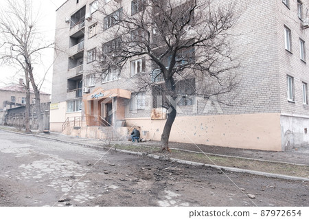 Mariupol, Ukraine - March 5, 2022: Men warm up and prepare food on bonfire outside hotel Nautical under bombardment 87972654