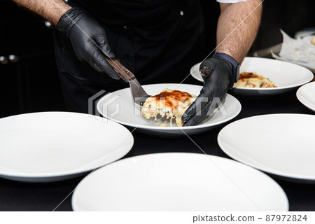 Chief serving potato gratin with chanterelles mushrooms and cheese in a restaurant 87972824