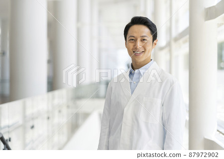 Image of a male medical worker / researcher in his thirties smiling looking at the camera in a white coat 87972902