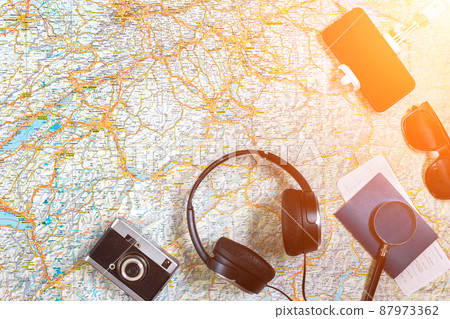 Accessories for travel. Passport, photo camera, smart phone and travel map. Top view. Sun flare 87973362