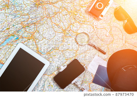 Accessories for travel. Passport, photo camera, smart phone and travel map. Top view. Sun flare Accessories for travel. Passport, photo camera, smart phone and travel map. Top view. Sun flare 87973470
