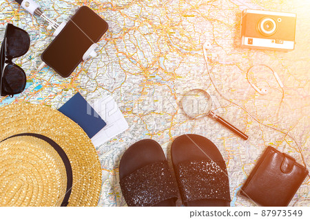Accessories for travel. Passport, hat, smart phone and travel map. Top view. Sun flare Accessories for travel. Passport, hat, smart phone and travel map. Top view. Sun flare 87973549