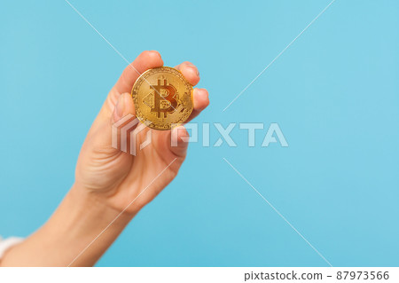 Closeup of hand holding golden bitcoin against blue background, advertising btc coin, copy space for cryptocurrency commercial, digital money, electronic investment. indoor studio shot, isolated Closeup of hand holding golden bitcoin against blue background, advertising btc coin, copy space for cryptocurrency commercial, digital money, electronic investment. indoor studio shot, isolated 87973566