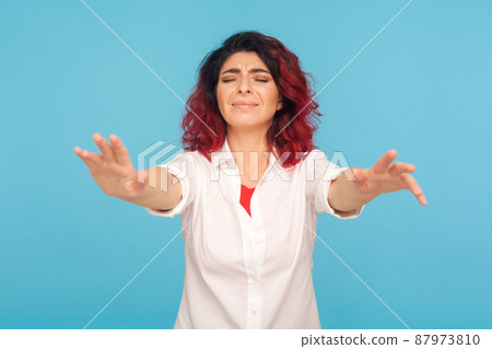 I'm blind. Portrait of frustrated woman with fancy red hair walking with closed eyes, stretching hands to search way in darkness, vision problems. indoor studio shot isolated on blue background I'm blind. Portrait of frustrated woman with fancy red hair walking with closed eyes, stretching hands to search way in darkness, vision problems. indoor studio shot isolated on blue background 87973810